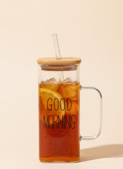 Good Morning glass mug with a sustainable bamboo lid and reusable glass straw, filled with a green drink.