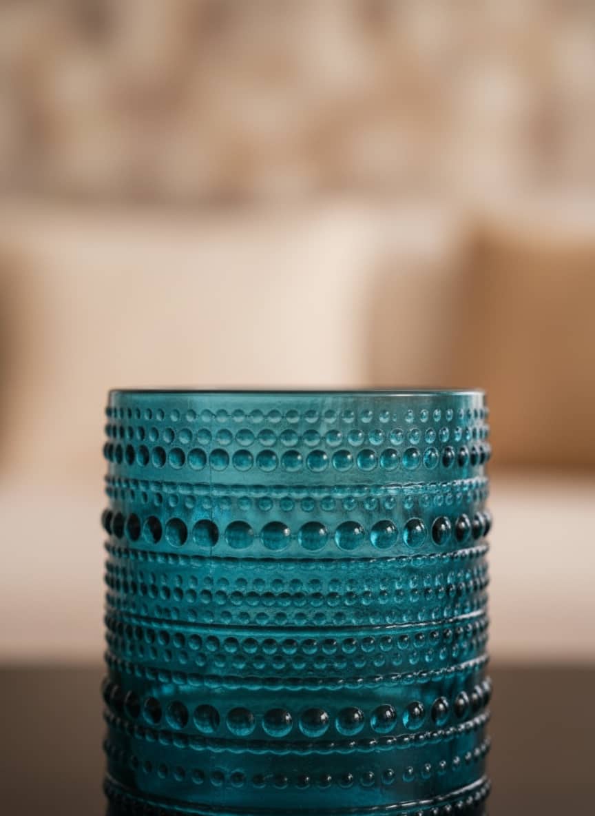 Close-up of a textured turquoise glass tumbler showing the durable raised dot and line pattern.