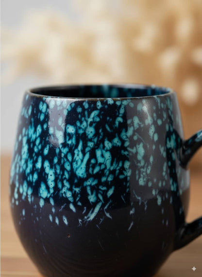 Close-up of the textured speckled glaze and smooth, comfortable handle on a handmade ceramic cup.
