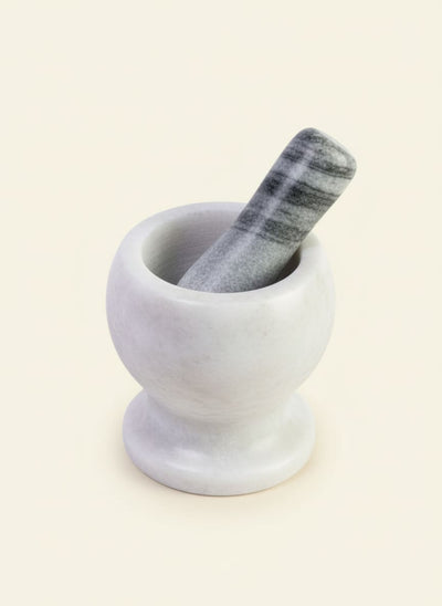White marble mortar with a grey and white striped marble pestle on a white background.