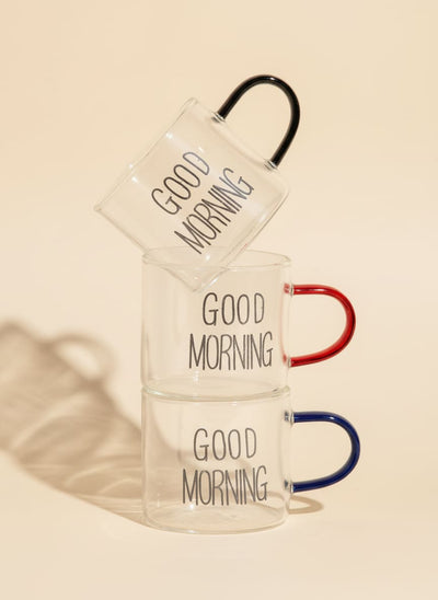 Stack of three Good Morning glass mugs with red, blue, and black handles.