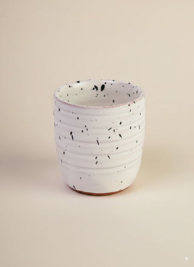 Handmade white speckled pottery tumbler with a natural terracotta base.