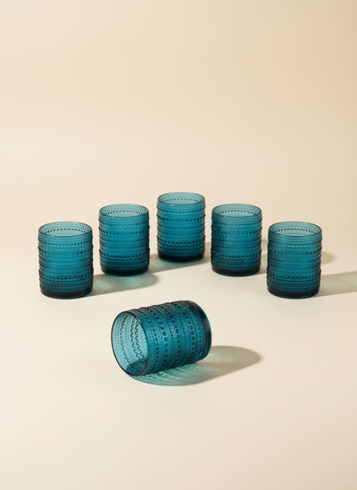 Set of six turquoise glass tumblers with a raised dot pattern, arranged on a white background.